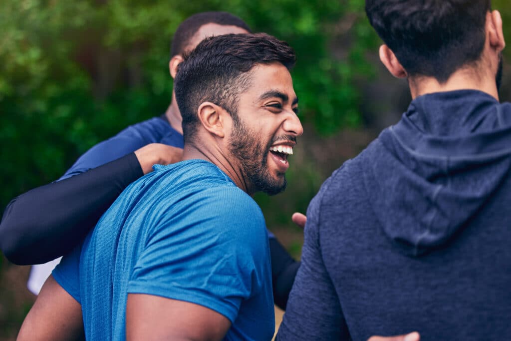 Happy, men and friends laughing for fitness, workout and running outdoor with a smile. Exercise, training and sports with funny joke and comedy together in nature with an Indian man with wellness iStock 1680016200