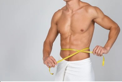 A man wrapping a tape measure around his waist after a weight loss program in Jacksonville