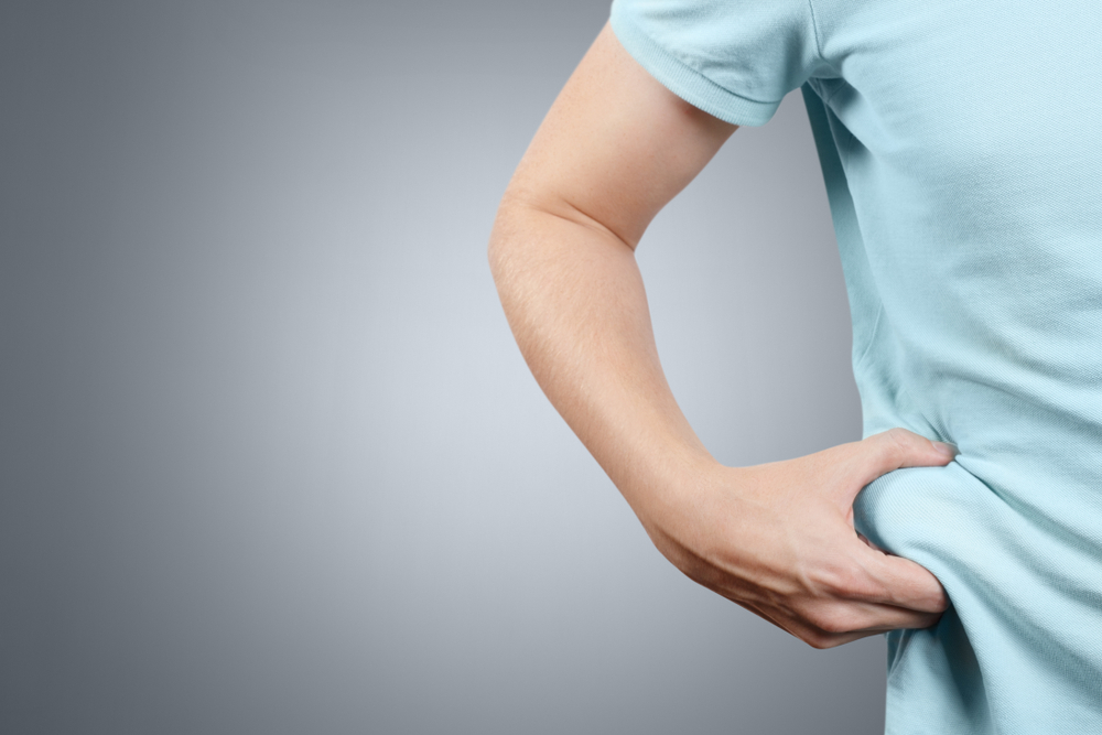 Man pinching belly fat, representing weight gain despite eating better and exercising. Man pinching belly fat, representing weight gain despite eating better and exercising.